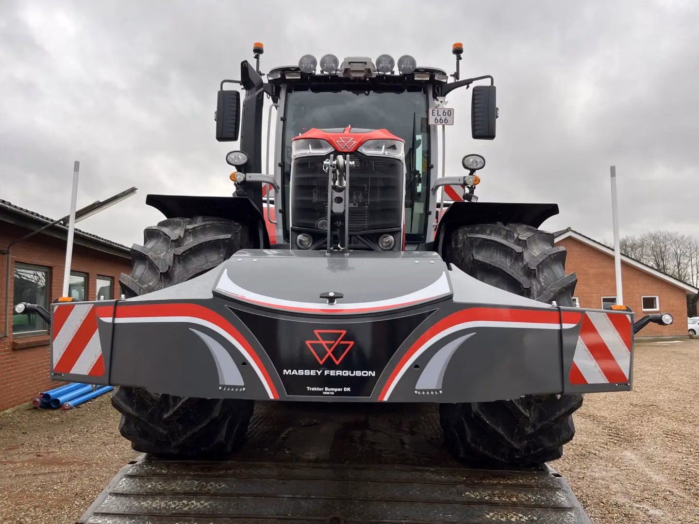 Front view of a large tractor with a gray and red Massey Ferguson bumper weight featuring reflective stripes