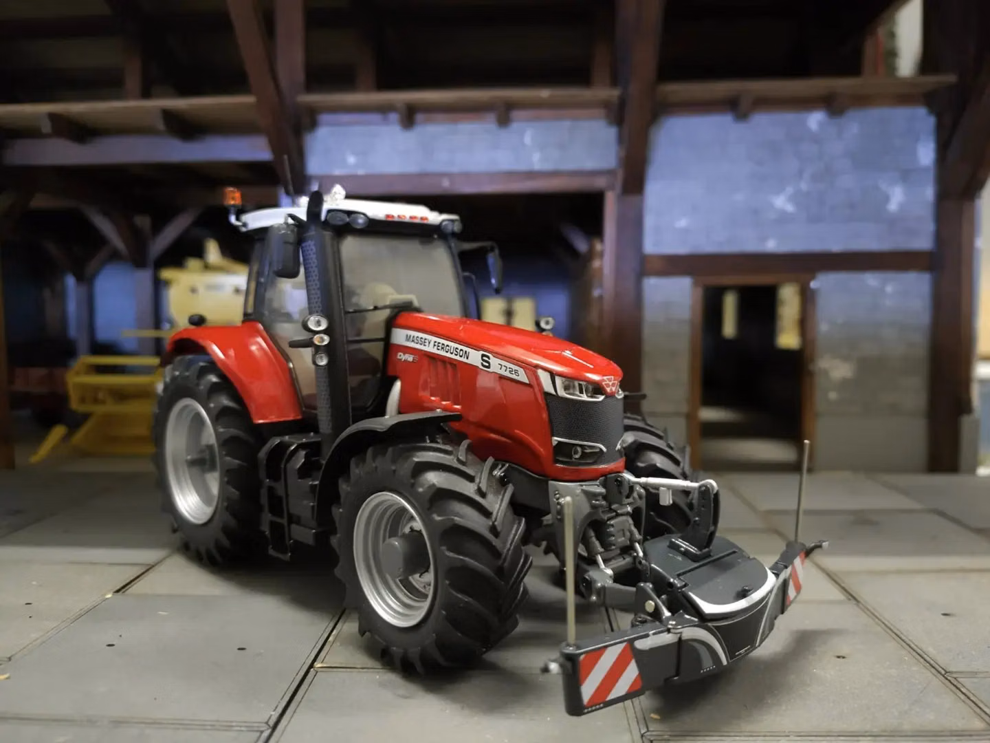 Red Massey Ferguson tractor with front weight bumper and LED lights attached, shown indoors on concrete flooring