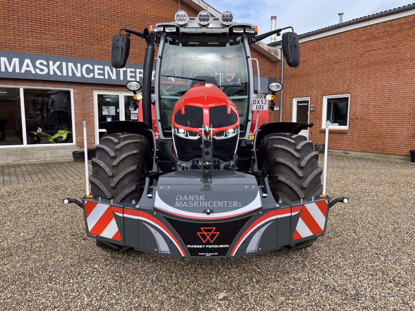 A Massey Ferguson tractor with a large front weight bumper featuring reflective red and white safety markings