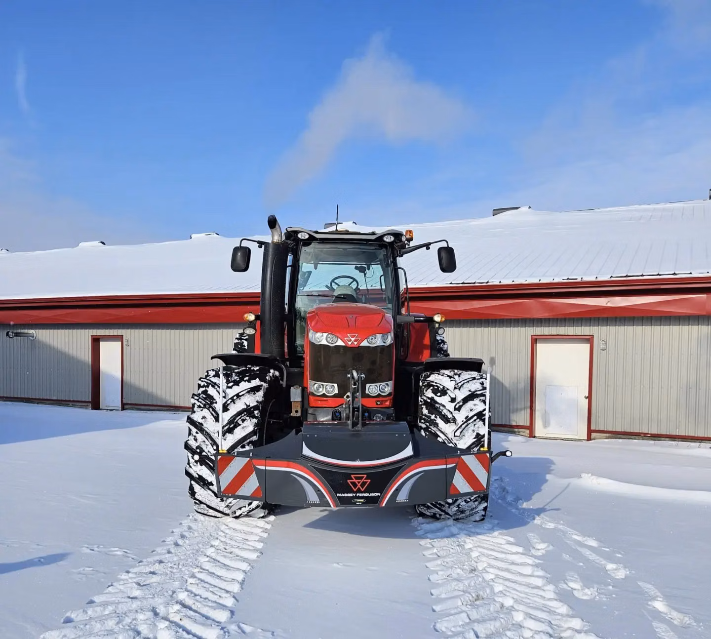 Red Massey Ferguson tractor with a front weight bumper and LED lights, parked on snow in front of a building