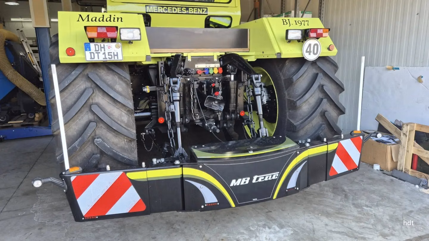 Large tractor rear view in a garage featuring an MB trac branded front weight bumper with reflective red and white panels