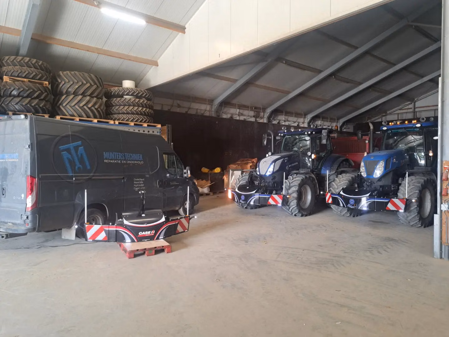 Two blue tractors in a shed display mounted front weight bumpers with LED lights and reflective panels