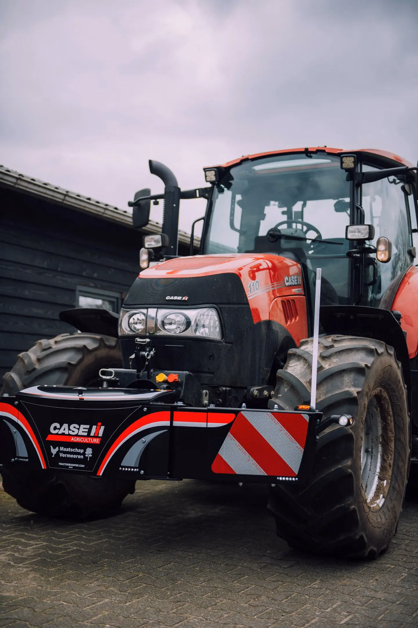 Red tractor with a mounted front weight bumper featuring reflective stripes and CASE IH branding