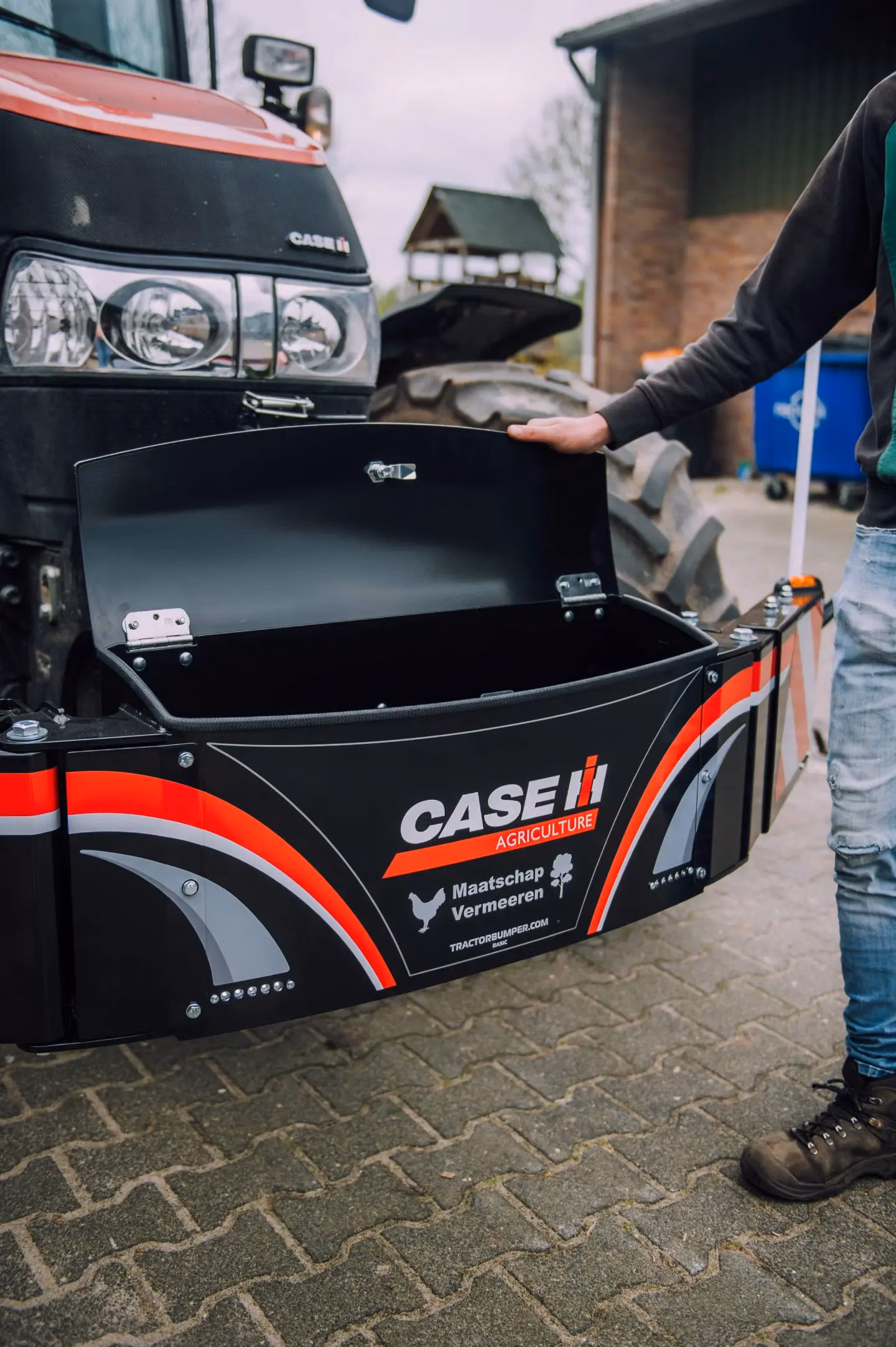 A person opens the lid of a CASE IH branded front weight bumper attached to a tractor.