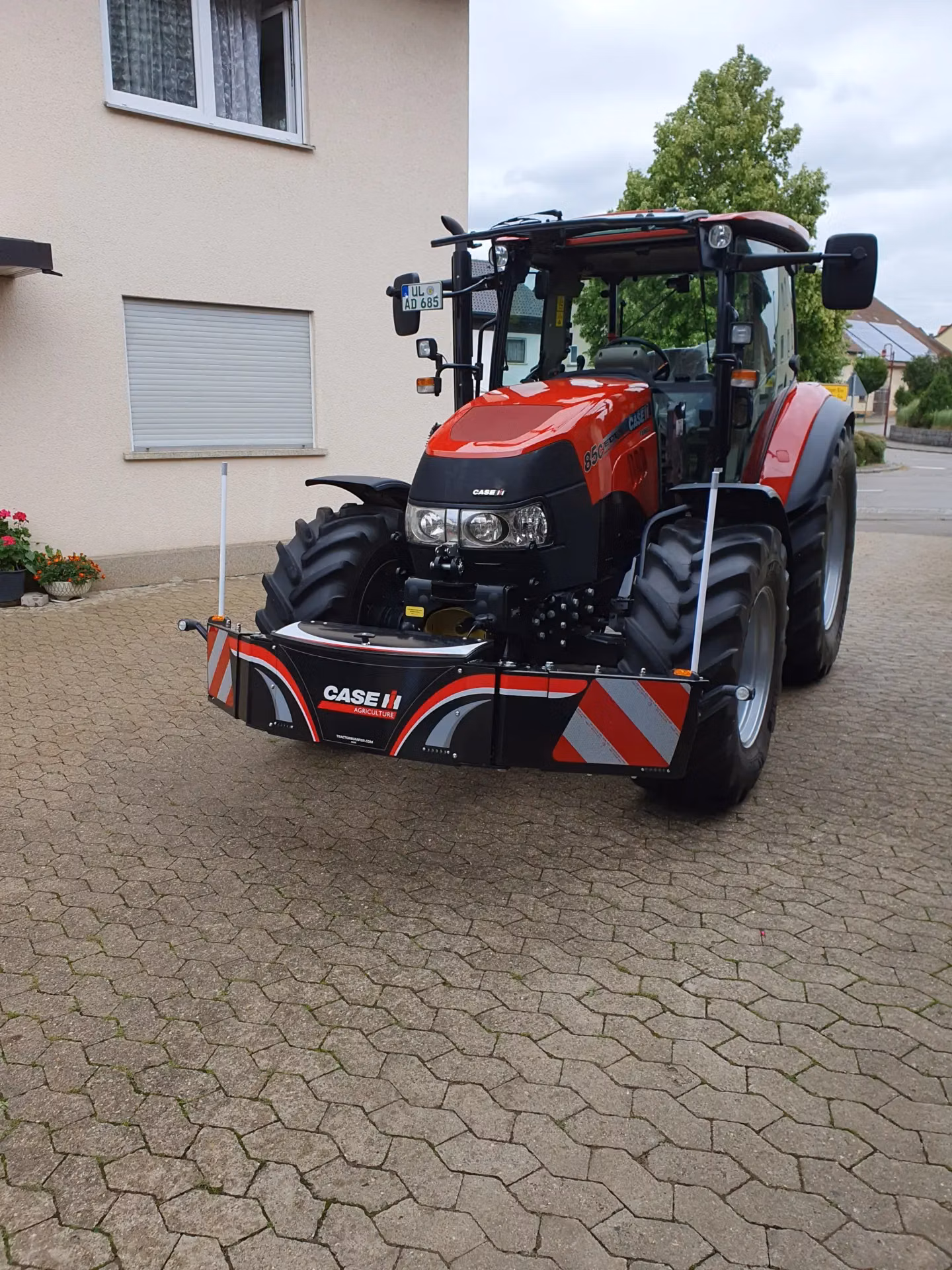 Red tractor with a front weight bumper featuring CASE IH branding and reflective red and white stripes