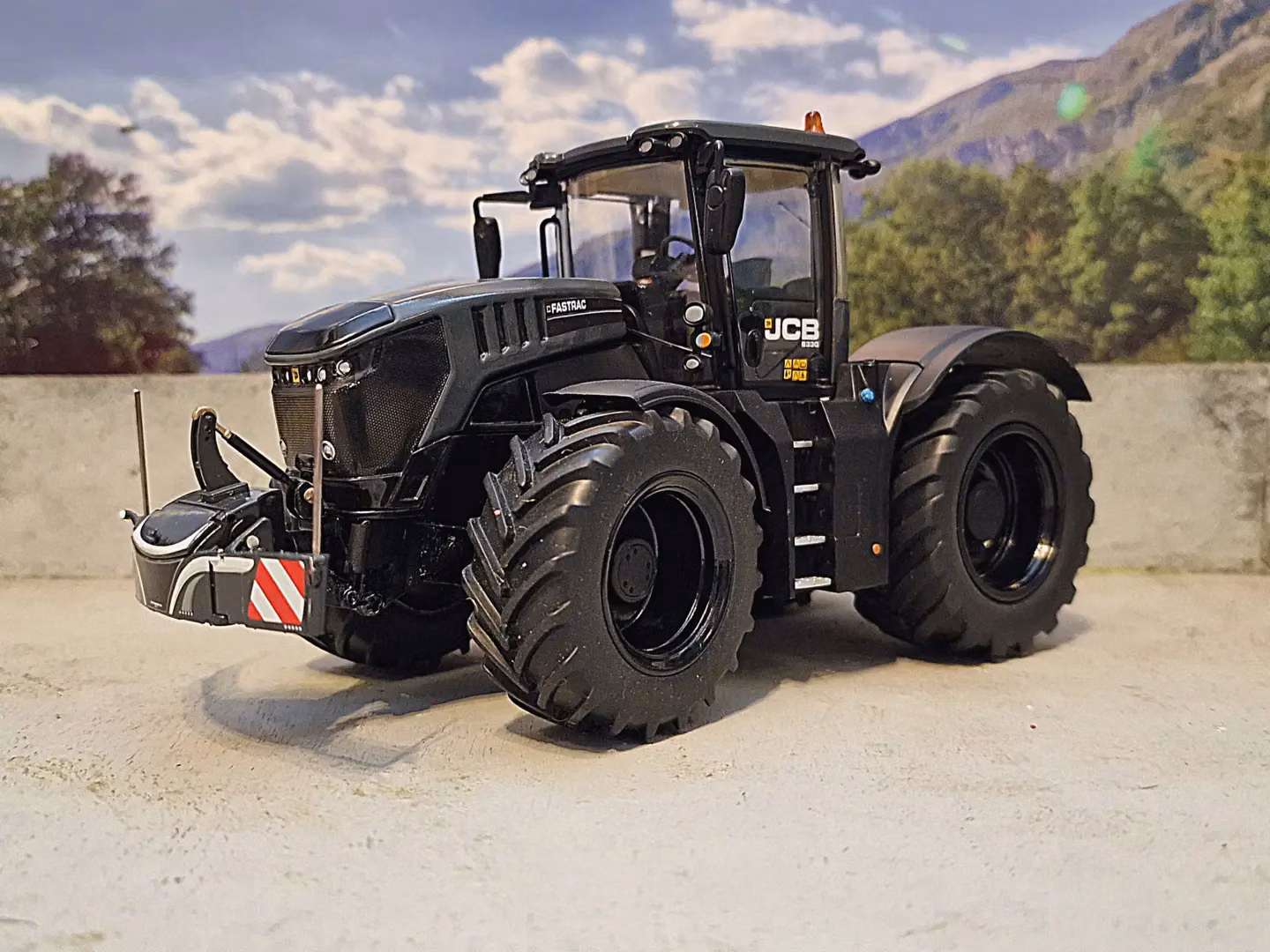 A black tractor with large tires is fitted with a front weight bumper featuring red and white hazard stripes