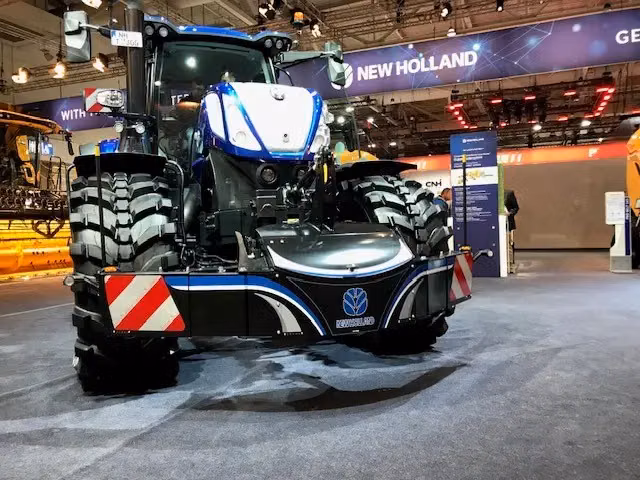 Blue tractor fitted with a front weight bumper featuring reflective red and white safety markings on each side