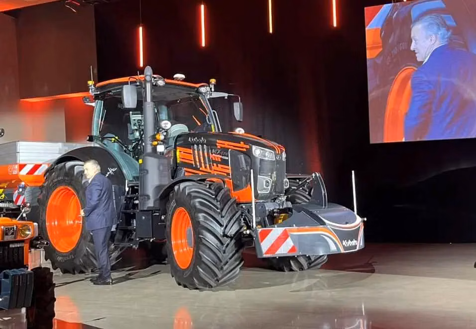 A front weight bumper with red and white safety stripes mounted on a large tractor at an indoor event