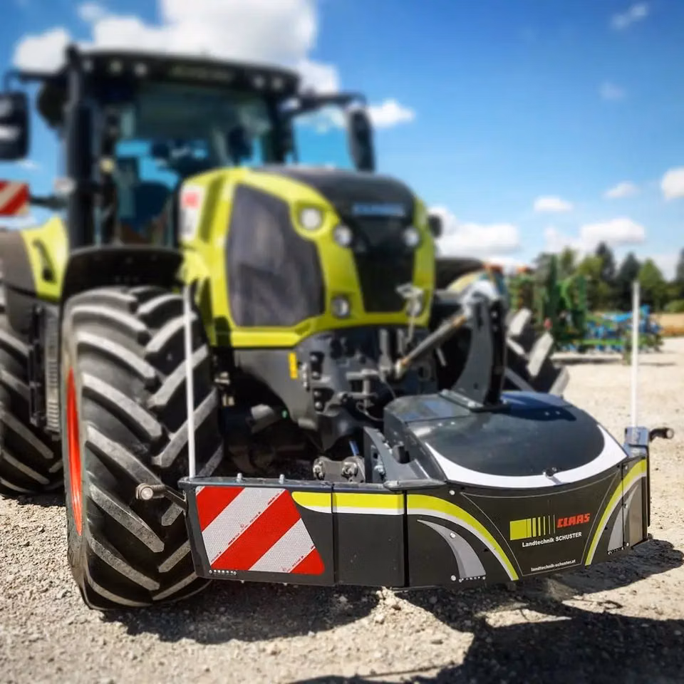 A close-up view of a tractor with a front weight bumper featuring red and white reflective panels and Claas branding