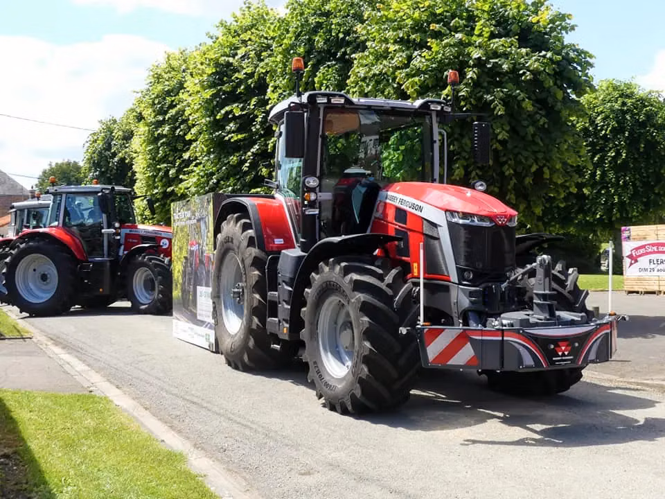 A red tractor fitted with a front weight bumper featuring reflective stripes and LED lights, parked on a road