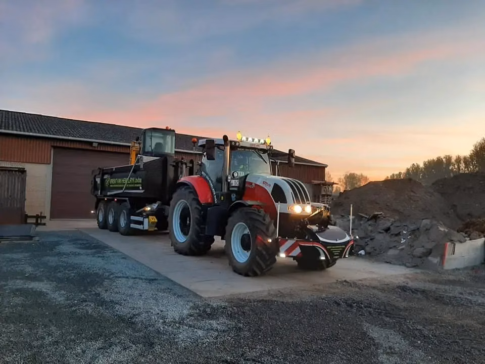 Tractor with headlights on, fitted with a front weight bumper featuring LED lighting and storage compartment